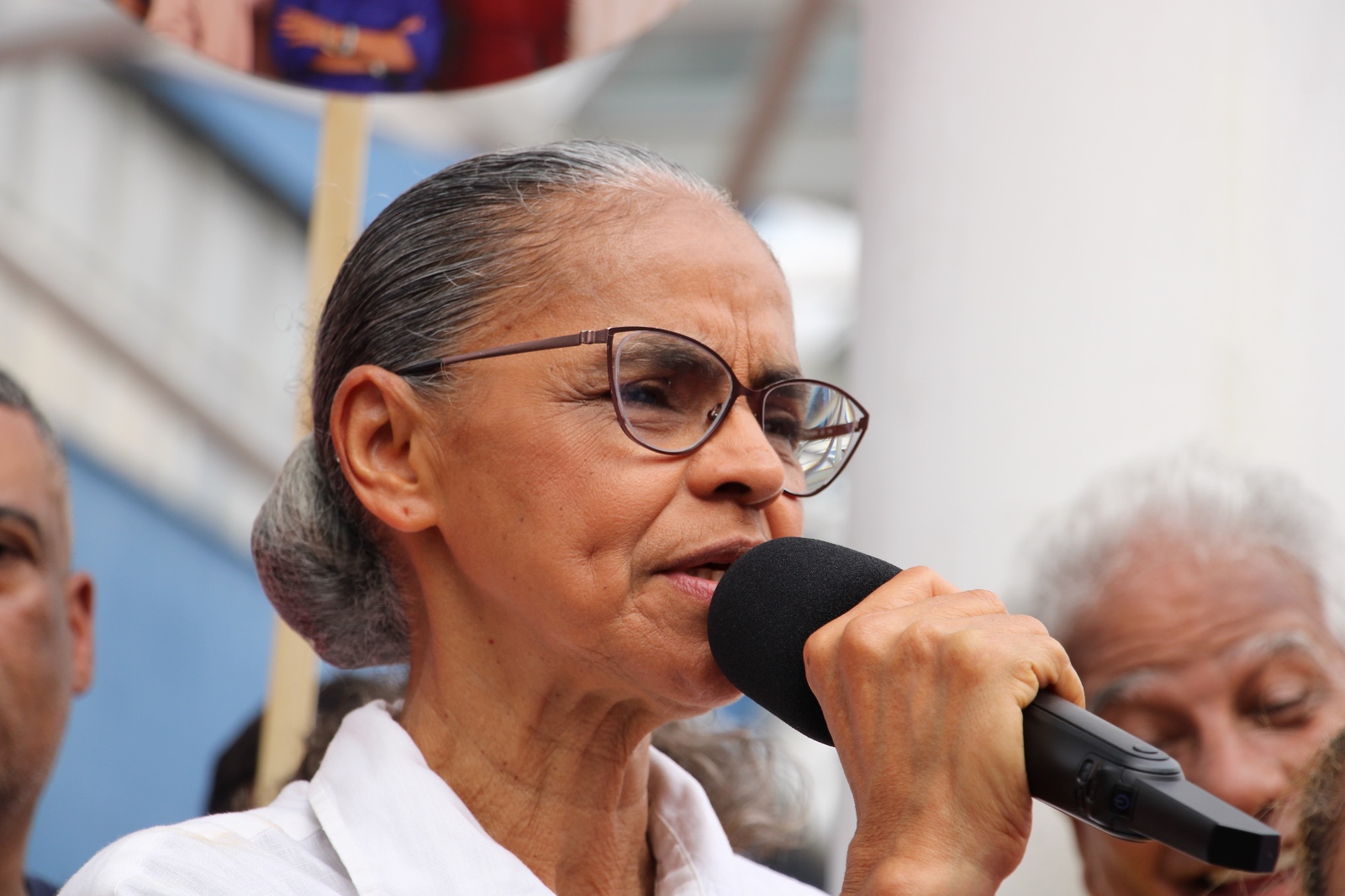 Marina Silva fala ao microfone durante a mobilização do PT em Osasco, usando óculos e camisa branca.