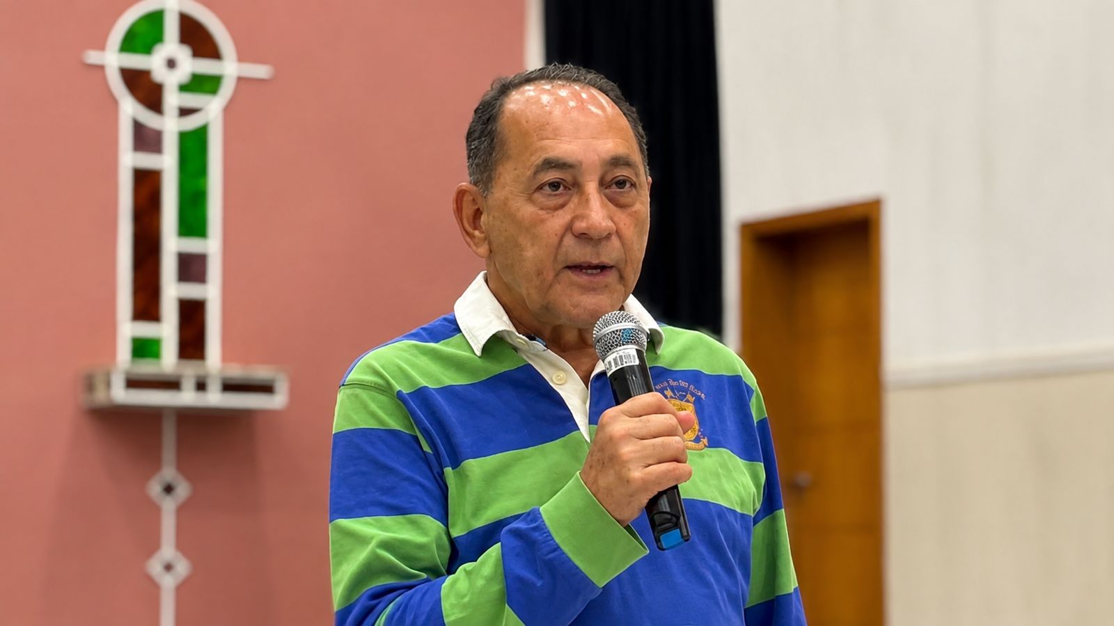 Homem segura um microfone e fala durante plenária com servidores públicos municipais.