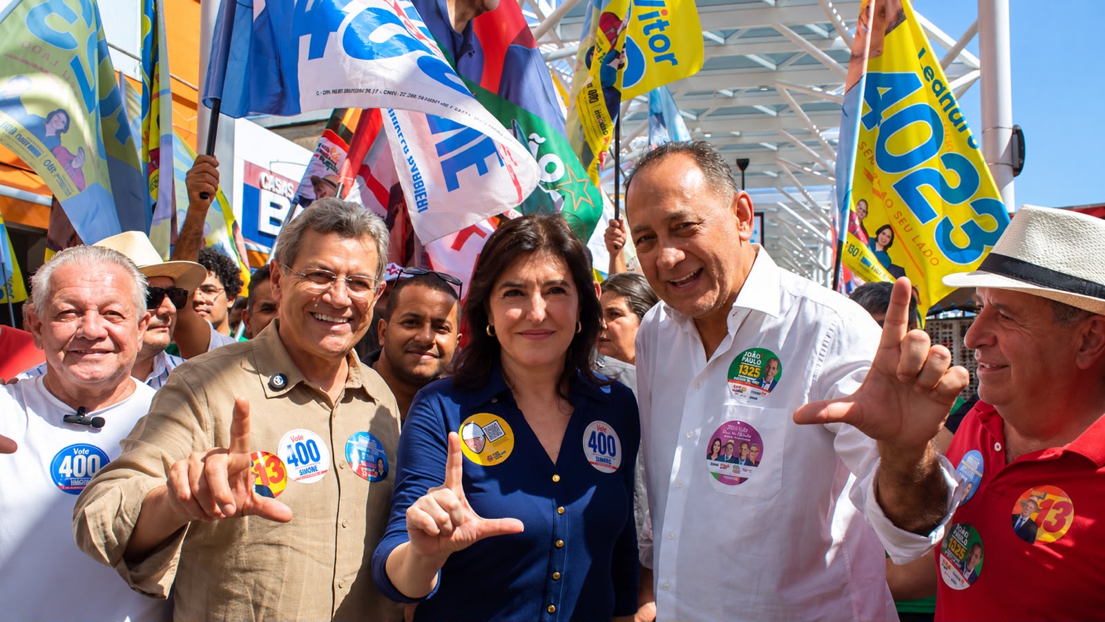 Emidio de Souza, Simone Tebet e João Paulo Cunha aparecem juntos durante caminhada política em Osasco, cercados por apoiadores e bandeiras de campanha.